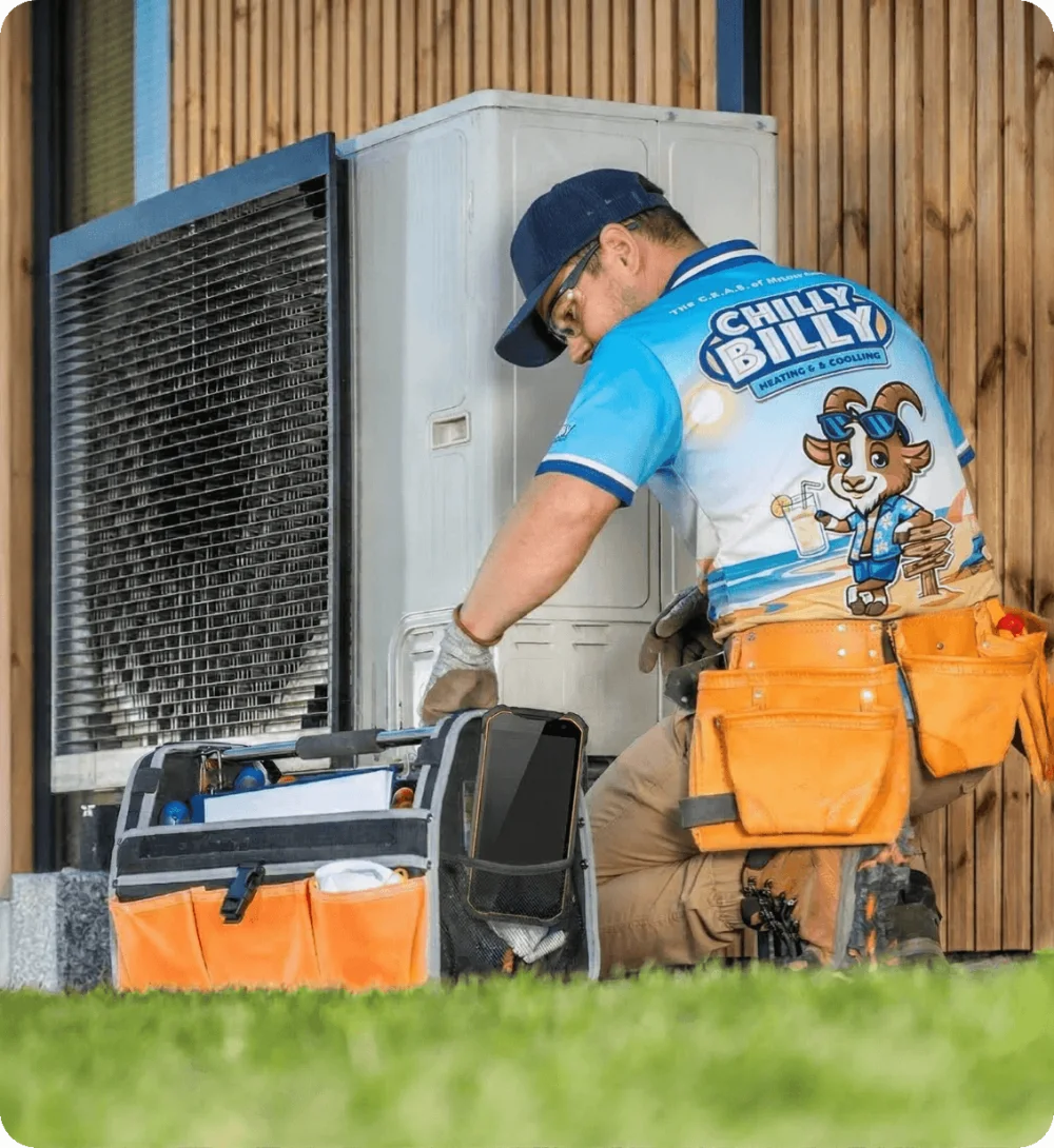 A Chilly Billy technician in a branded polo servicing an outdoor AC condenser unit at a Central Florida home